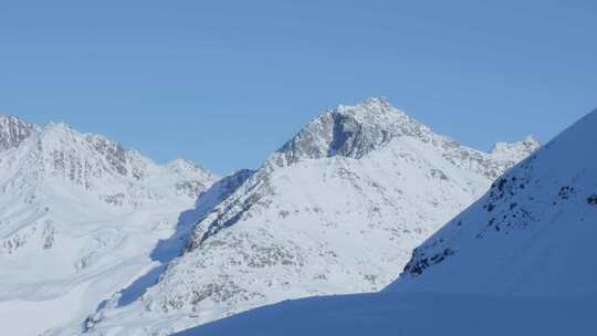白雪皑皑的山峰和山脊，明亮阳光明媚的冬日，阿尔卑斯山的蓝天
