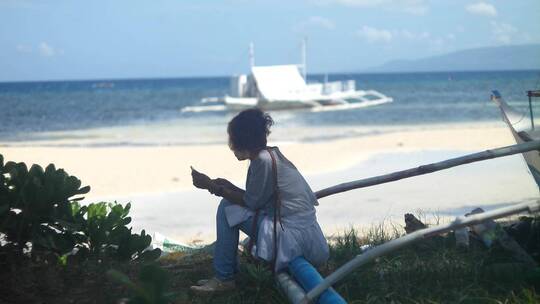 女人坐在海边微笑着挥手视频素材模板下载