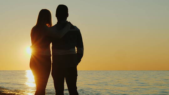 一对夫妇站在海边看日落
