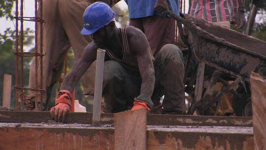 建筑工人用长板打磨混凝土