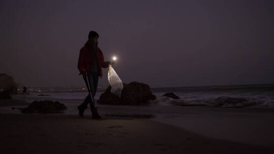 夜晚女人在海滩上拾垃圾