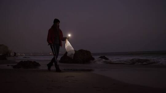 夜晚女人在海滩上拾垃圾视频素材模板下载