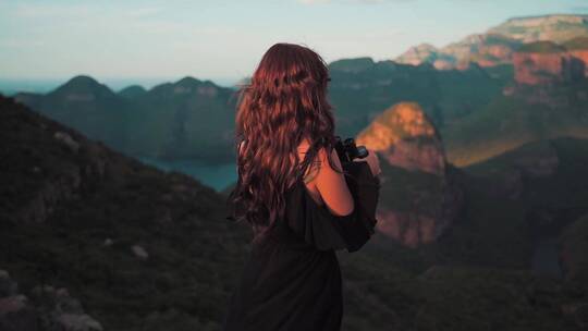 女人用望远镜欣赏山景