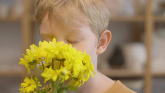 一个金发孩子闻黄色的花