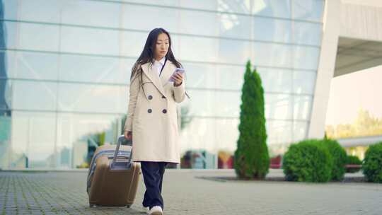 亚洲女旅游女商人带着手提箱从航站楼机场背