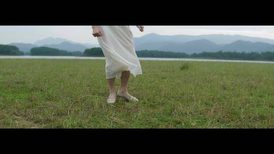 白色连衣裙女子在草原上跳舞舞步特写