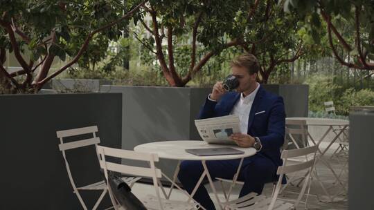 商人坐在户外喝咖啡看报纸视频素材模板下载