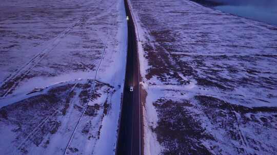 傍晚行驶在雪地公路的汽车