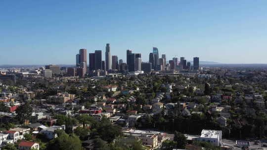无人机飞过标志性的洛杉矶棕榈树林立的街道，背景是城市天际线。