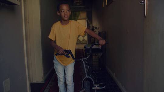 男孩推着自行车从楼道走出