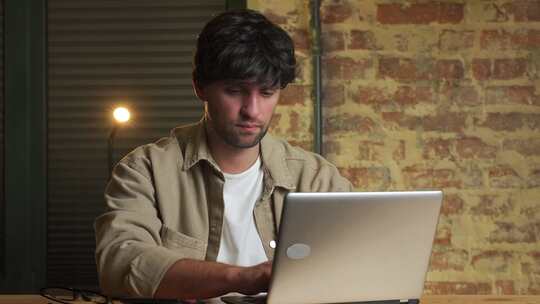 一个梦幻般的男人坐在办公桌前，在笔记本电脑上思考解决问题的肖像