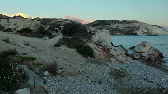 游客们在日落时分探索阿芙罗狄蒂的岩石，漫