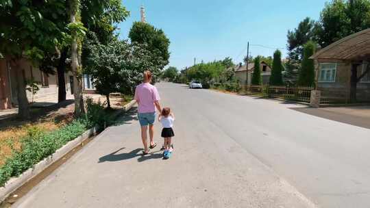 一个小女孩骑着踏板车，妈妈走在她旁边