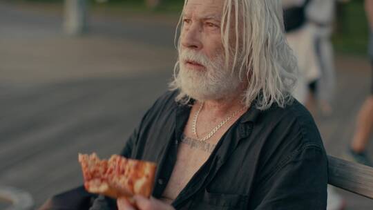 老年艺术家在街头吃披萨