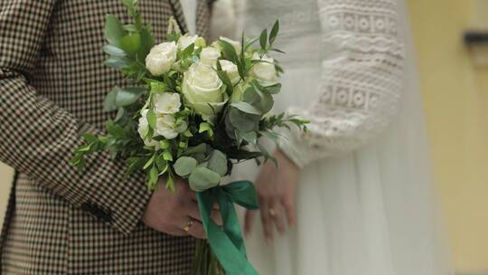 新郎和新娘的手抚摸着婚礼花束