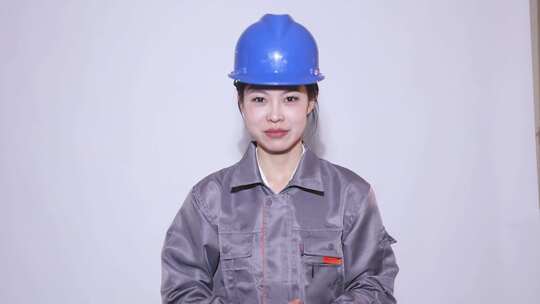 中国女孩戴蓝色安全帽工人服装做手势