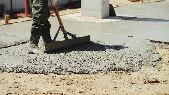 建筑工人在建筑工地找平液态混凝土