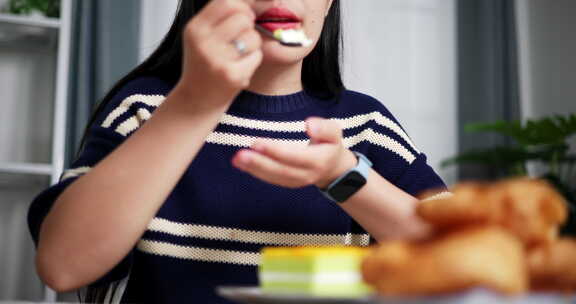 年轻的亚洲女人喜欢在家里的餐桌上吃早餐。