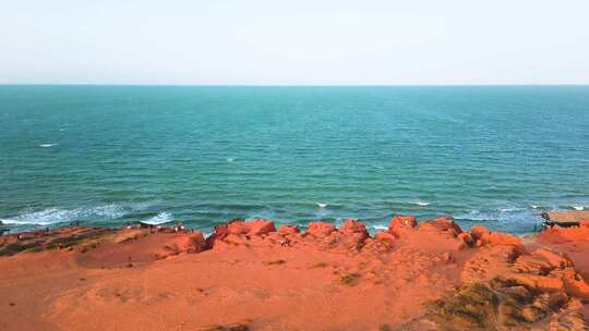 红色沙崖与碧绿海水相映的海边风景