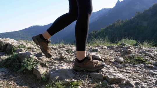 徒步登山妇女在悬崖顶上徒步的脚在岩石上行