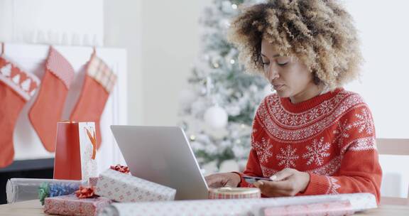 圣诞树旁在电脑输入银行卡的女孩