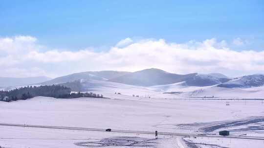 辽阔雪地上的公路与周边山脉风景