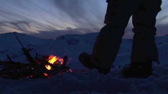 冬天男人在营火旁暖脚