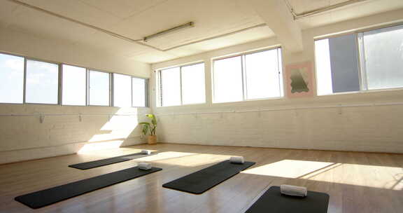 明亮的瑜伽馆设有黑色垫子、白色墙壁和带复