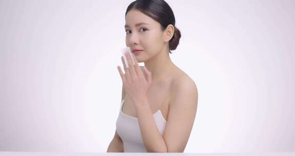 年轻迷人的亚洲女人用棉垫轻轻清洁脸部的美丽肖像
