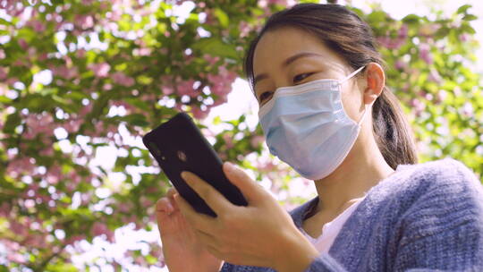 亚洲人中国女性戴口罩户外办公打电话玩手机视频素材模板下载