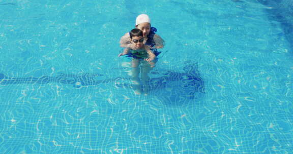 夏天游泳池小男孩和妈妈一起游泳玩耍