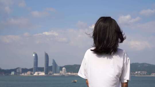 女孩站在城市海边吹风看风景看海青春少女