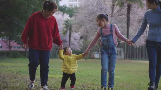大人牵手小孩在公园草地散步的场景