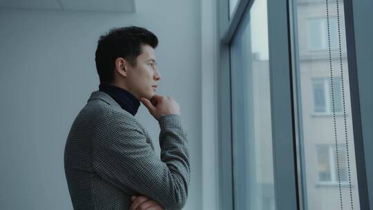 职场男人在窗户边看着窗外
