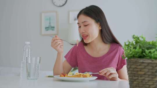 亚洲年轻女子在家客厅吃美式早餐。