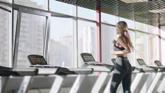 女人在健身房跑步机上跑步锻炼