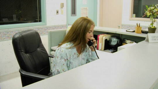女人在医院问讯处后面接电话