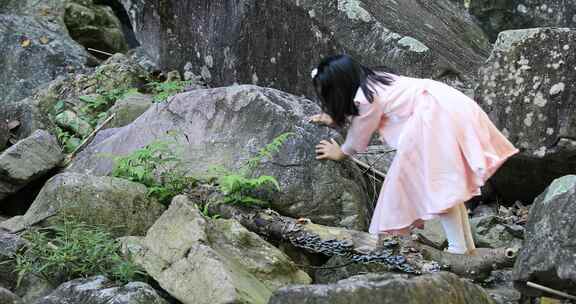小女孩在山野爬石头玩耍
