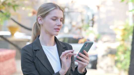 女商人在智能手机户外浏览互联网