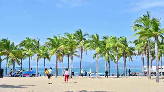 海南三亚西岛蓝天白云下的椰树沙滩与游客