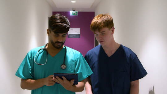两名医务人员在走廊里用平板电脑交谈