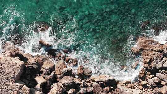 海岸线的空中俯视图，海浪撞击岩石海岸，产生白色泡沫视频素材模板下载