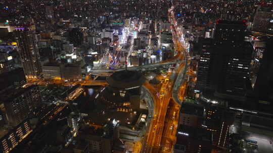 在大都市鸟瞰图中飞越夜间城市汽车通过多层