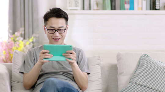 年轻男性在家里沙发上打手机游戏