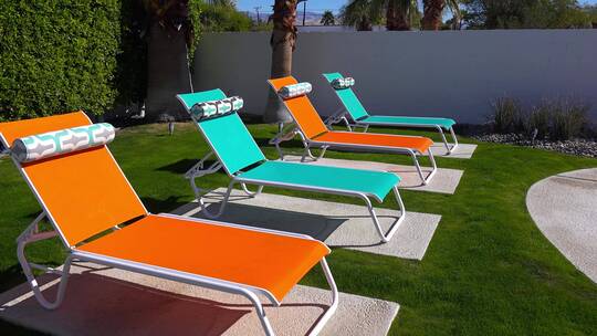 游泳池草坪上摆放的五颜六色的躺椅