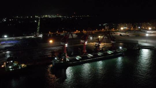 俯视夜间铁矿砂石厂塔吊施工运输船