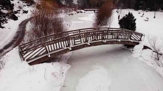 航拍公园被冰雪覆盖的小溪和桥梁
