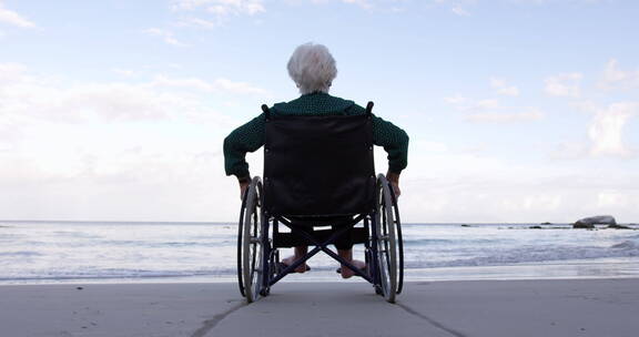 坐在轮椅上的老奶奶在海边张开双臂放松
