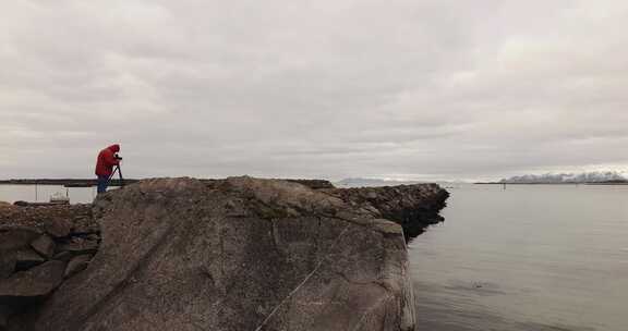 摄影师站在岩石上俯瞰海洋和山脉