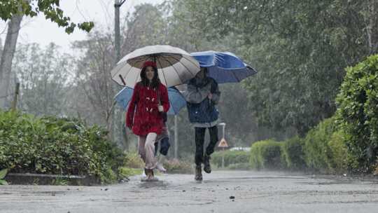 孩子们拿着雨伞一起在路上蹦蹦跳跳